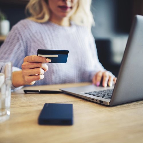 woman holding credit card while using laptop